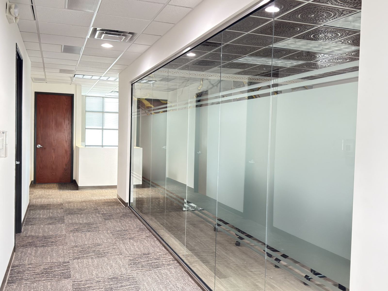 Modern office hallway with glass-walled offices and a wooden door conference room privacy with window film