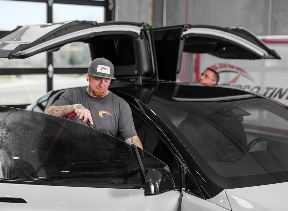 Professional window tint installer working on a car window tint inside bay window film turbo tint garage 