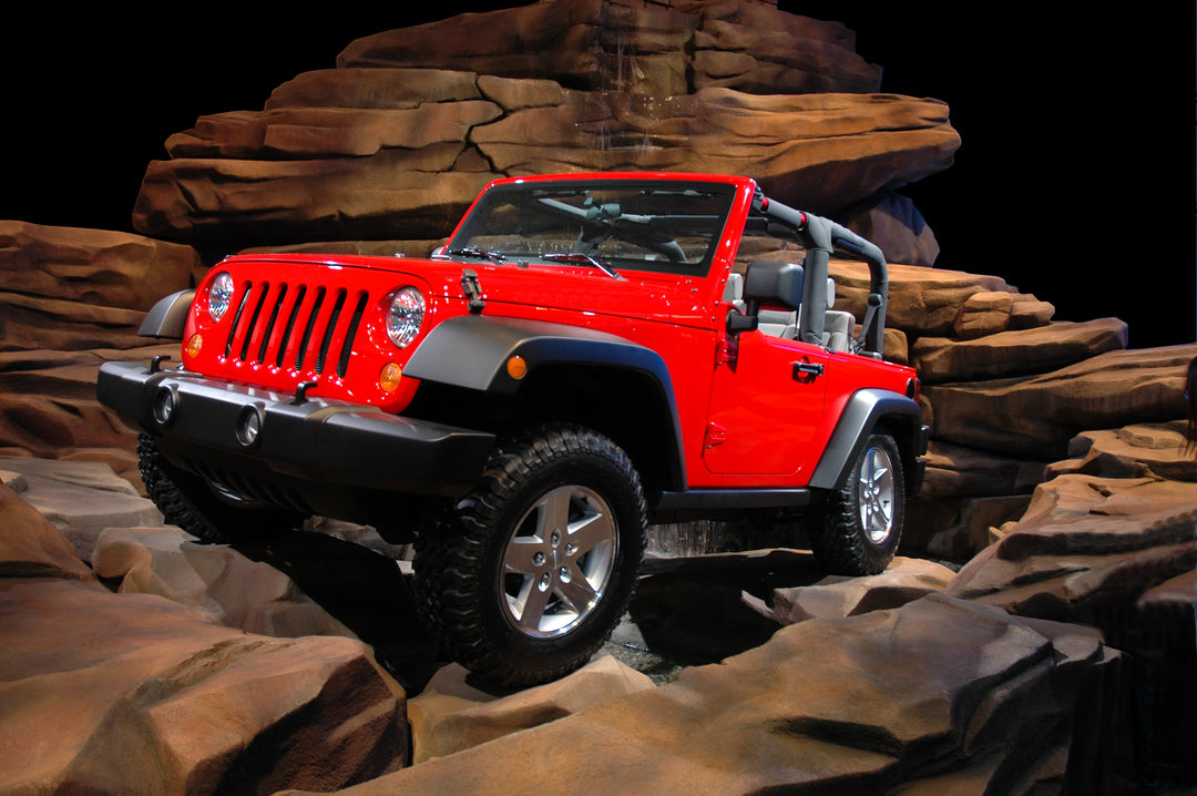 Red Jeep Wrangler on rocky terrain with a dark background, perfect for turbo tint clearplex windshield protection 