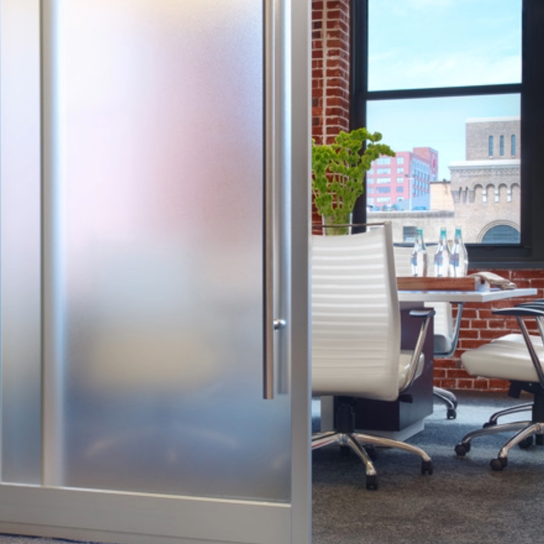 Frosted glass office door with a view of an office interior and cityscape.