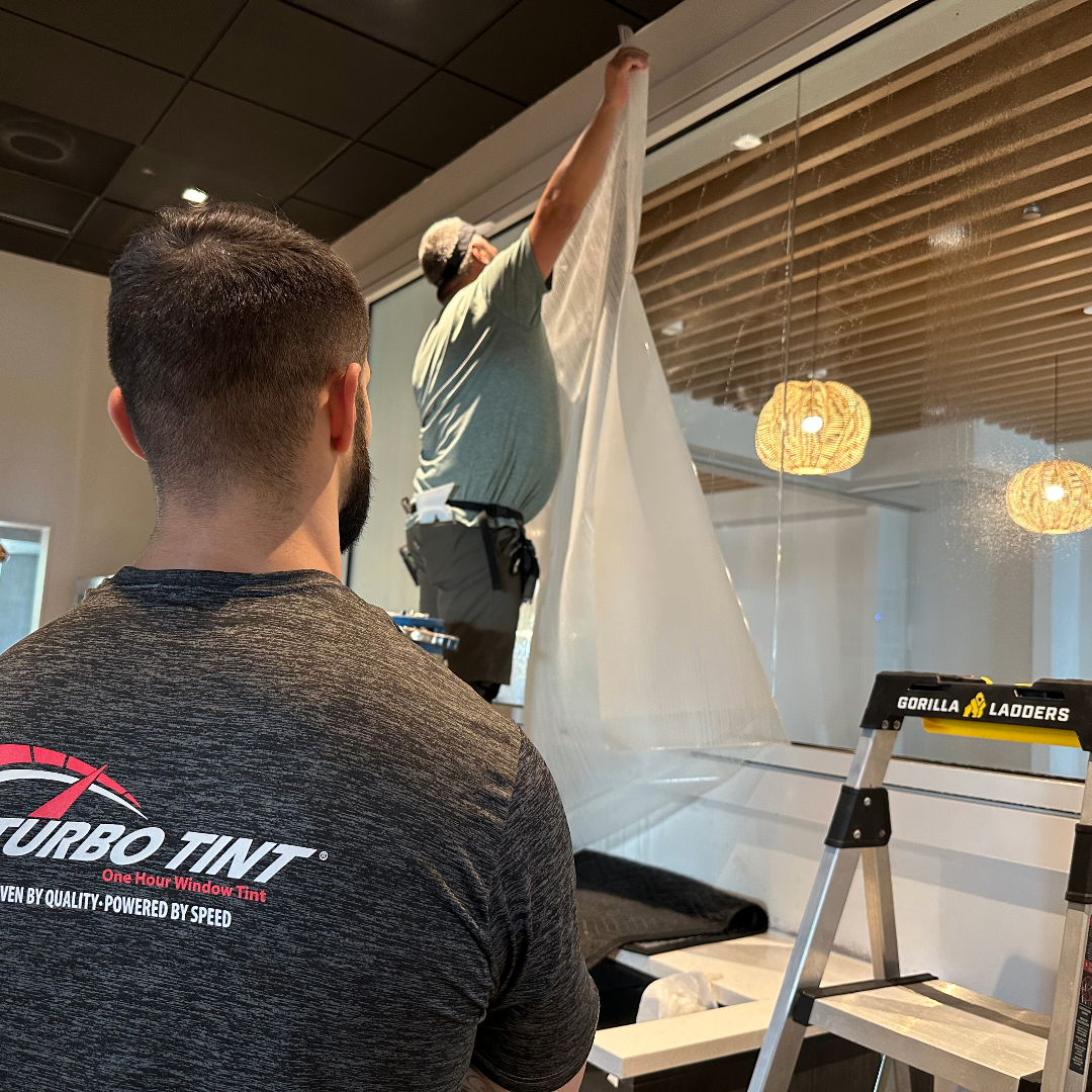 Two men installation on buisness window film conference room  window tinting with a ladder and Gorilla Ladders sign in the background.